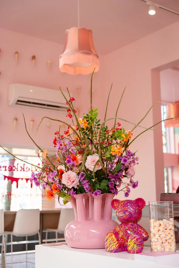 Roze vaas met kleurrijke bloemen en een beschilderd beertje in het interieur van IJs & Lekkers