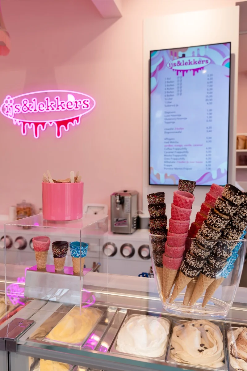 Sfeervolle interieur van IJs & Lekkers met roze neonbord, vitrine en gedecoreerde hoorntjes